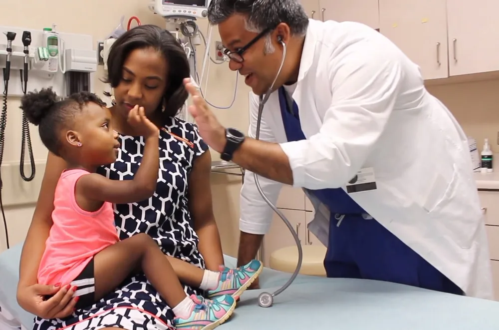 Dr. Mickey high-fiving a young patient during a pediatric exam