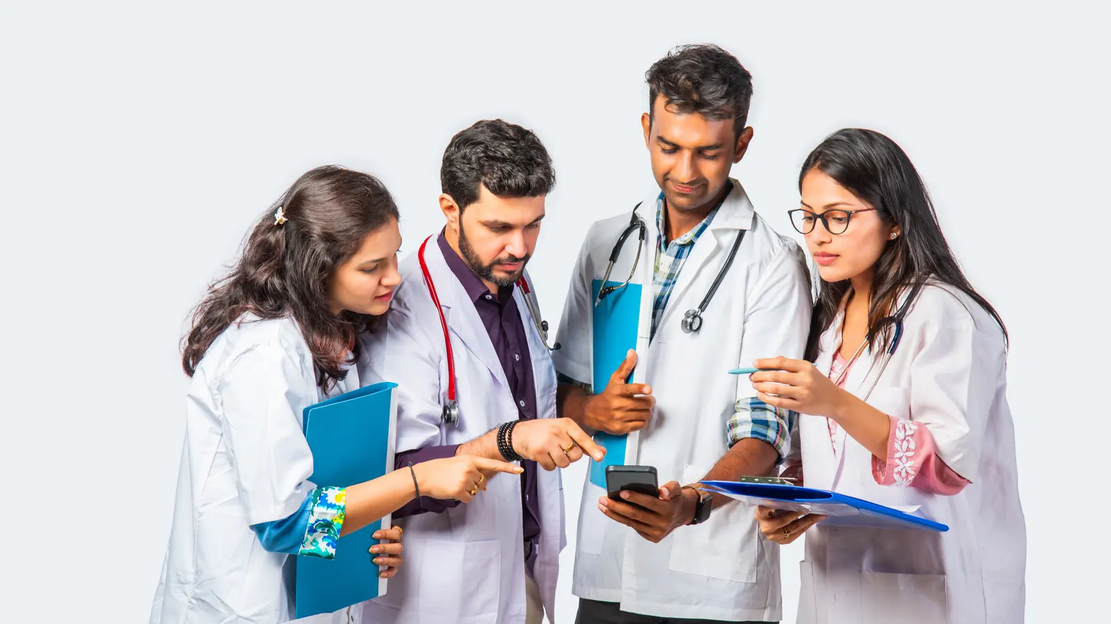 Four medical students in white coats looking at data on a phone together