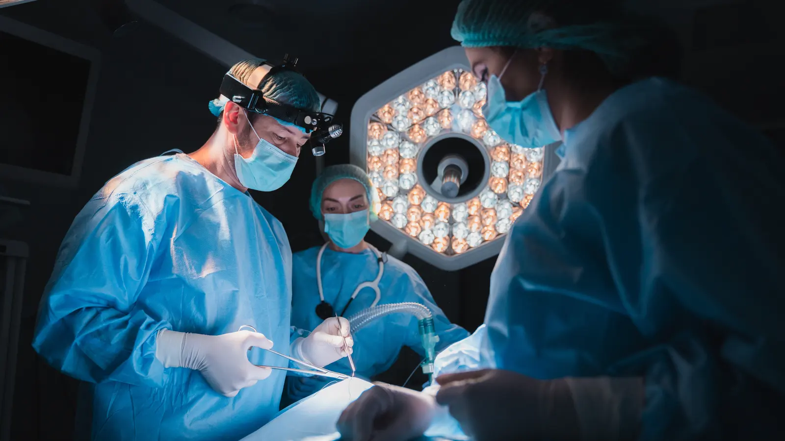 A surgical team operating under the lights of an operating room